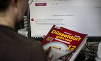 Mann sind vor Bildschirm, hat einen Gastroführer in der Hand