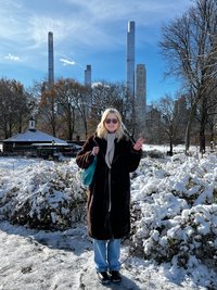 Frau im winterlichen New York, im Hintergrund eine Skyline.