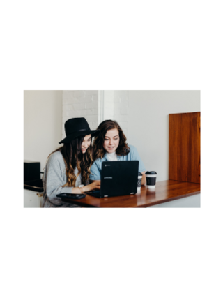 Zwei Mädchen schauen auf einen Laptop.