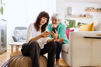 Eine Frau und eine Senioren schauen gemiensam auf ein Handy