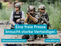 Soldaten und ein Reporter knien auf dem Boden