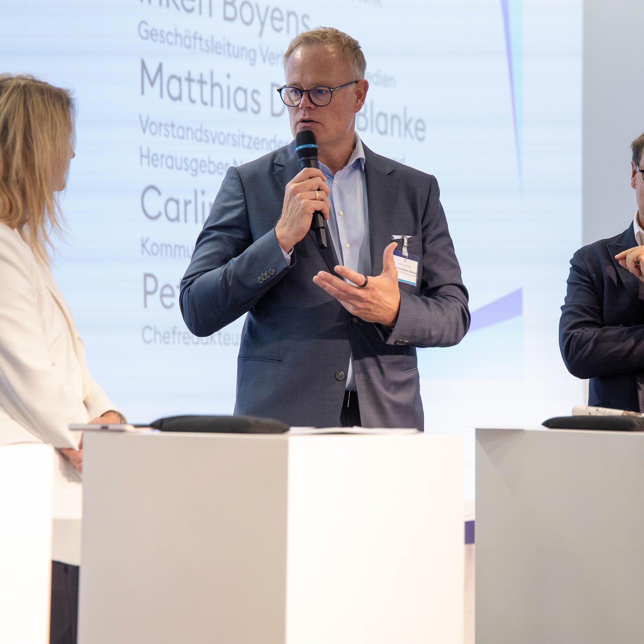 zwei Männer und eine Frau diskutieren auf Bühne