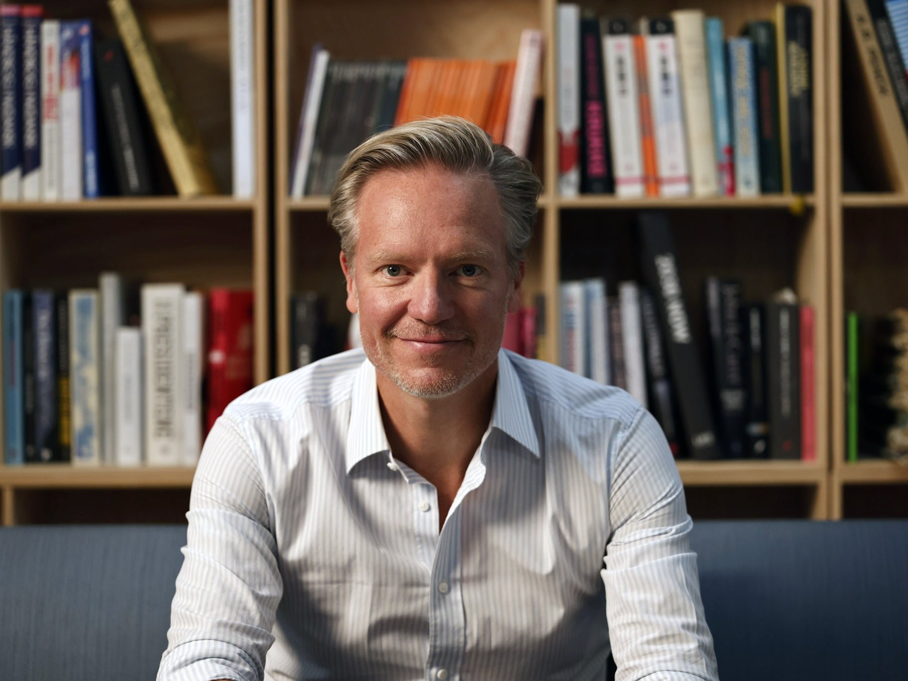 Mann sitzt auf Sofa vor einer Bücherwand