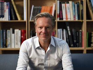 Mann sitzt auf Sofa vor einer Bücherwand