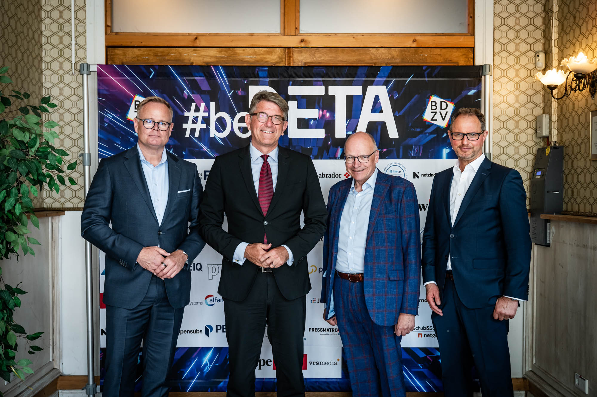 Vier Männer vor einer Fotowand auf der beBETA 2026