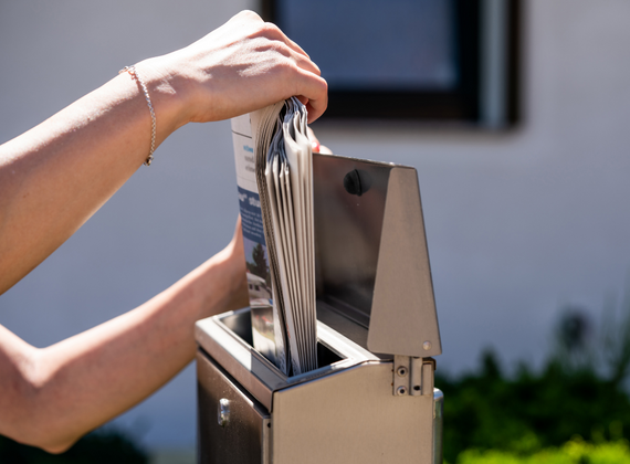 Eine Zeitung wird aus einem Briefkasten geholt