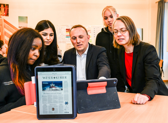 David Koopmann (Mi.), Vorstand der Bremer Tageszeitungen AG, zeigt Schülerinnen, wie das E-Paper des "Weser-Kurier" auf dem iPad aussieht.