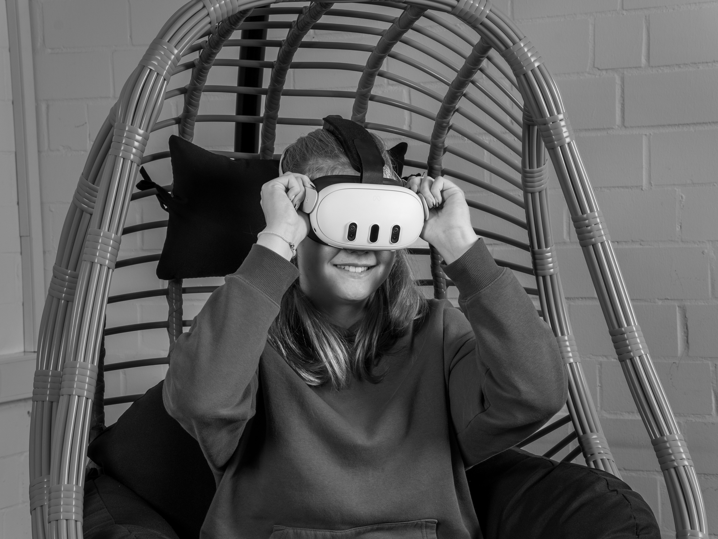 Mädchen sitzt in einem Hängesessel aus Korb und trägt eine VR-Brille