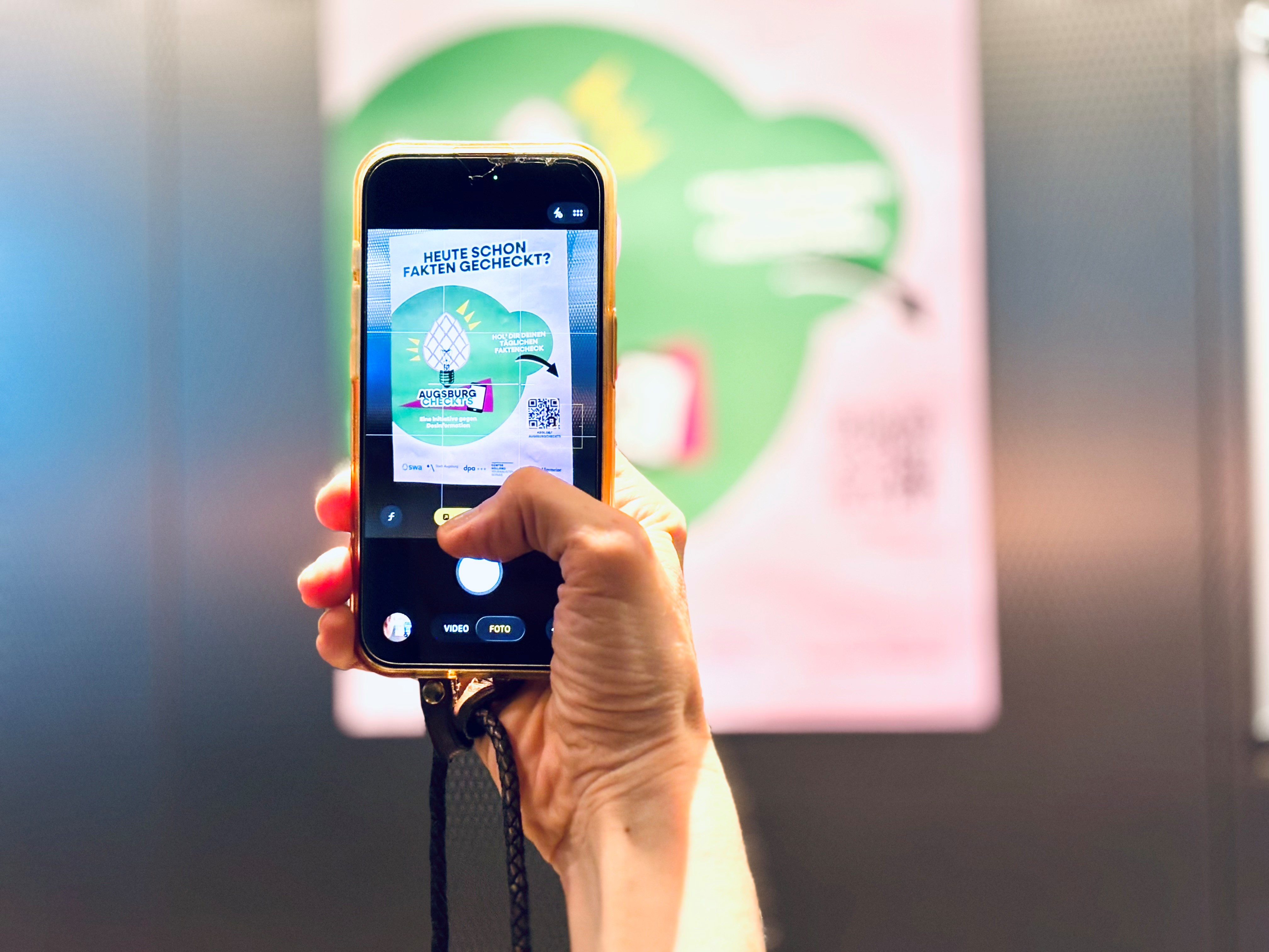 Augsburg Checkts Plakat wird mit dem Smartphone fotografiert