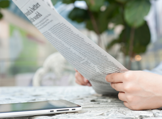 Ein Tablet liegt neben einer Printzeitung