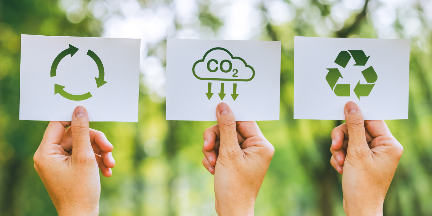 Drei Hände halten Schilderm mit Nachhaltigkeitssymbolen in der Hand.
